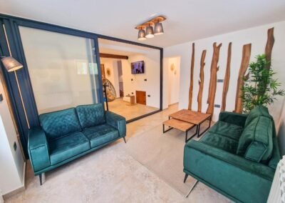 Wellness lounge with green sofas and glass sliding doors
