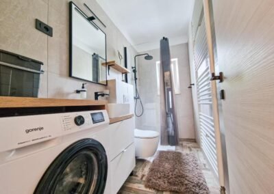 Bathroom with washing machine and glass shower