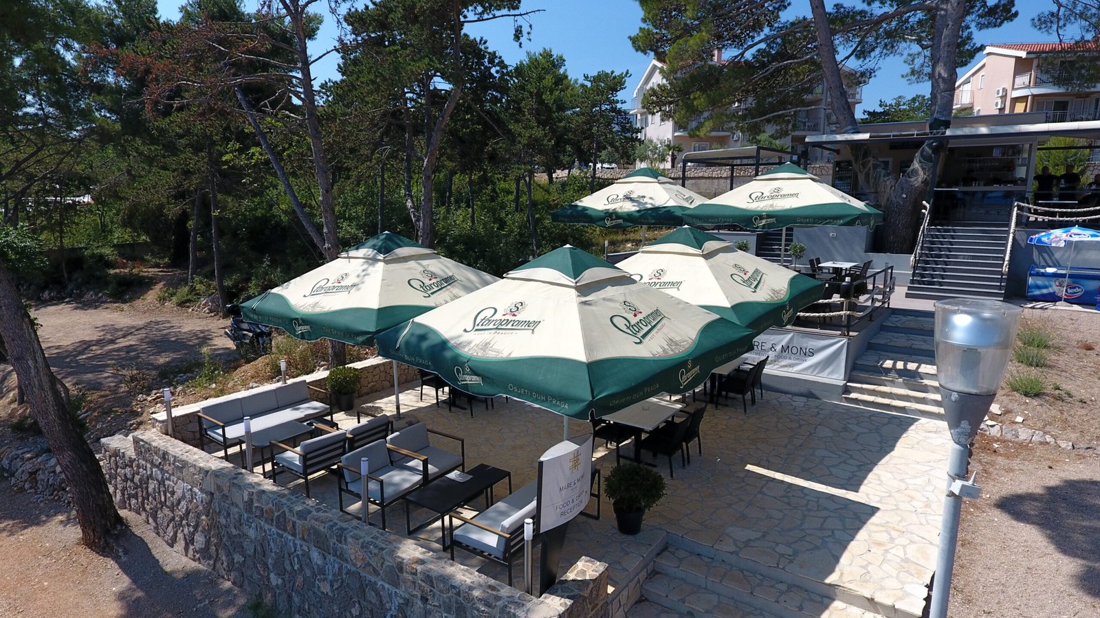 Bistro tables under green parasols overlooking the sea
