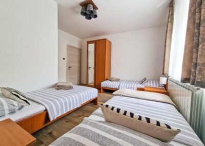 Three-bed room with striped bedding at Grga's Villa
